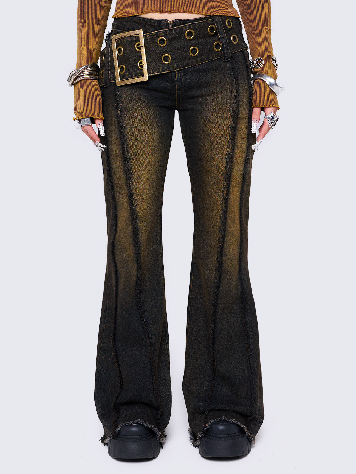 Black flared jeans featuring a honey overdye wash, a chunky buckle belt, distressed seams details and raw frayed hems. 