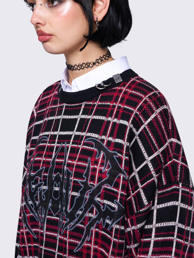 Plaid knitted jumper in red and black with a bold graphic print on the front. Features distressed rib details and a black ribbed neckline accented with piercing detail.