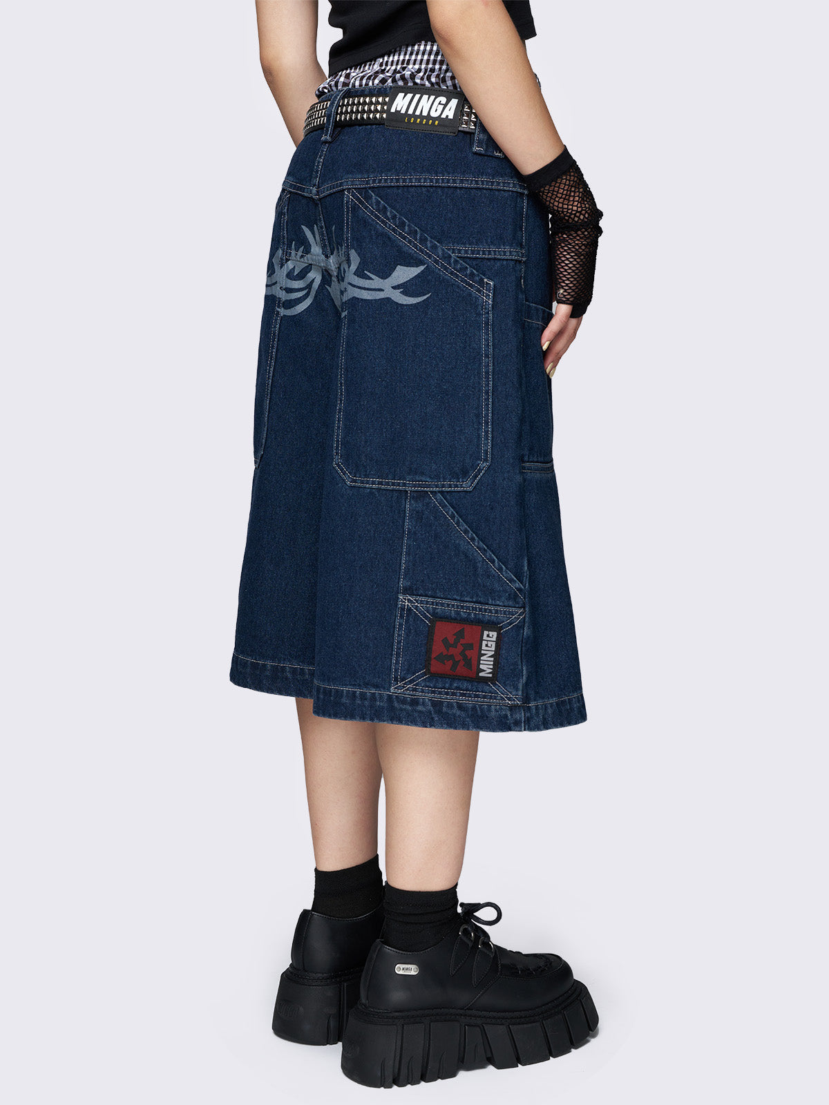 Blue longline denim shorts with carpenter pockets, a tattoo back print, and a relaxed fit. Featuring a regular waist and zip fly with button fastening.