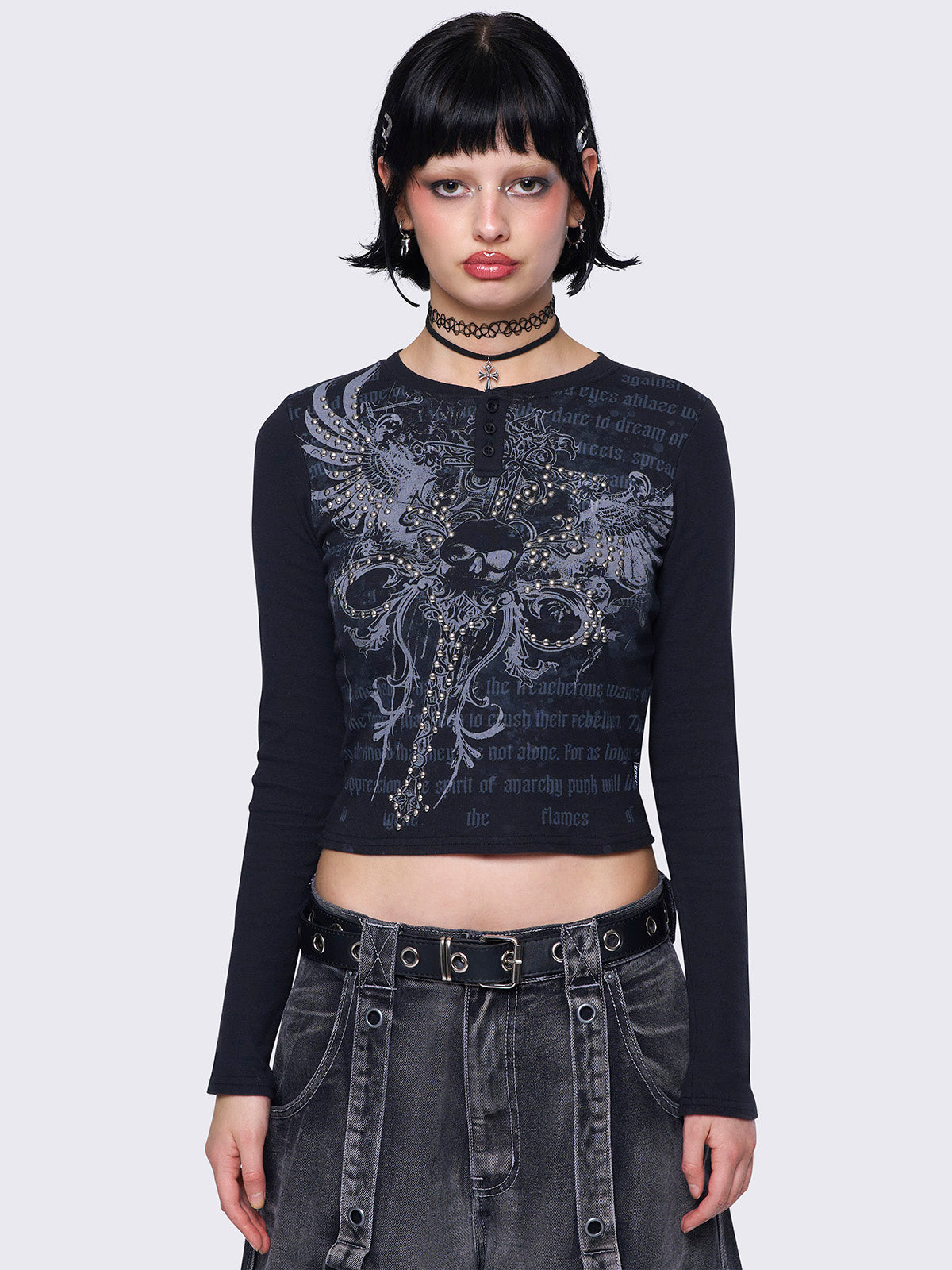 Black long-sleeve top with dagger skull graphic, studded details, slim fit, rounded neckline, and half button placket. Grunge and Y2K aesthetic