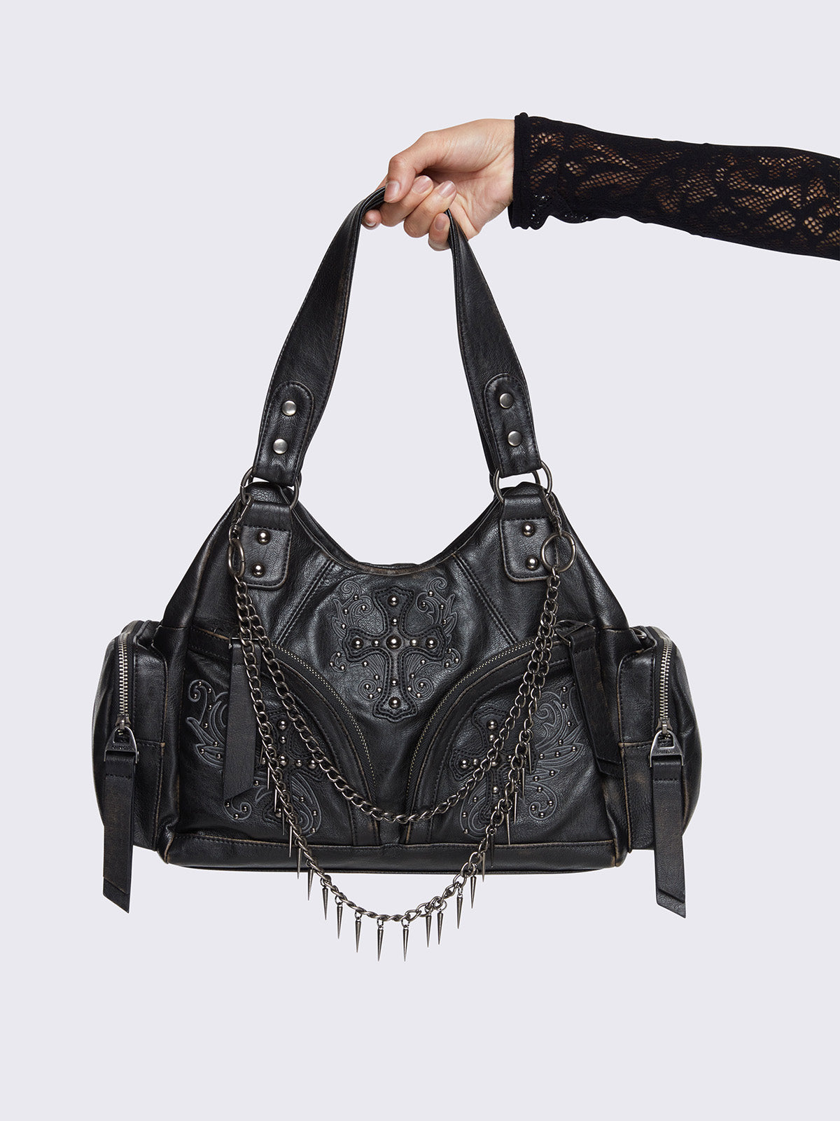 Washed black faux leather shoulder bag featuring studded cross patches, spike and chain accents, and multiple pockets.