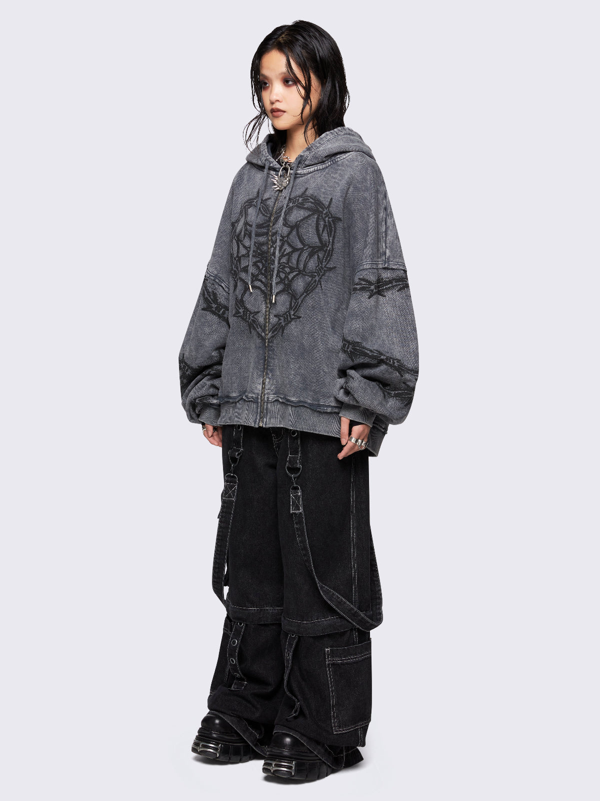 Grey distressed wash zip-up hoodie with a black barbed wire and spiderweb graphic, oversized fit, and dropped shoulders for a bold grunge aesthetic.