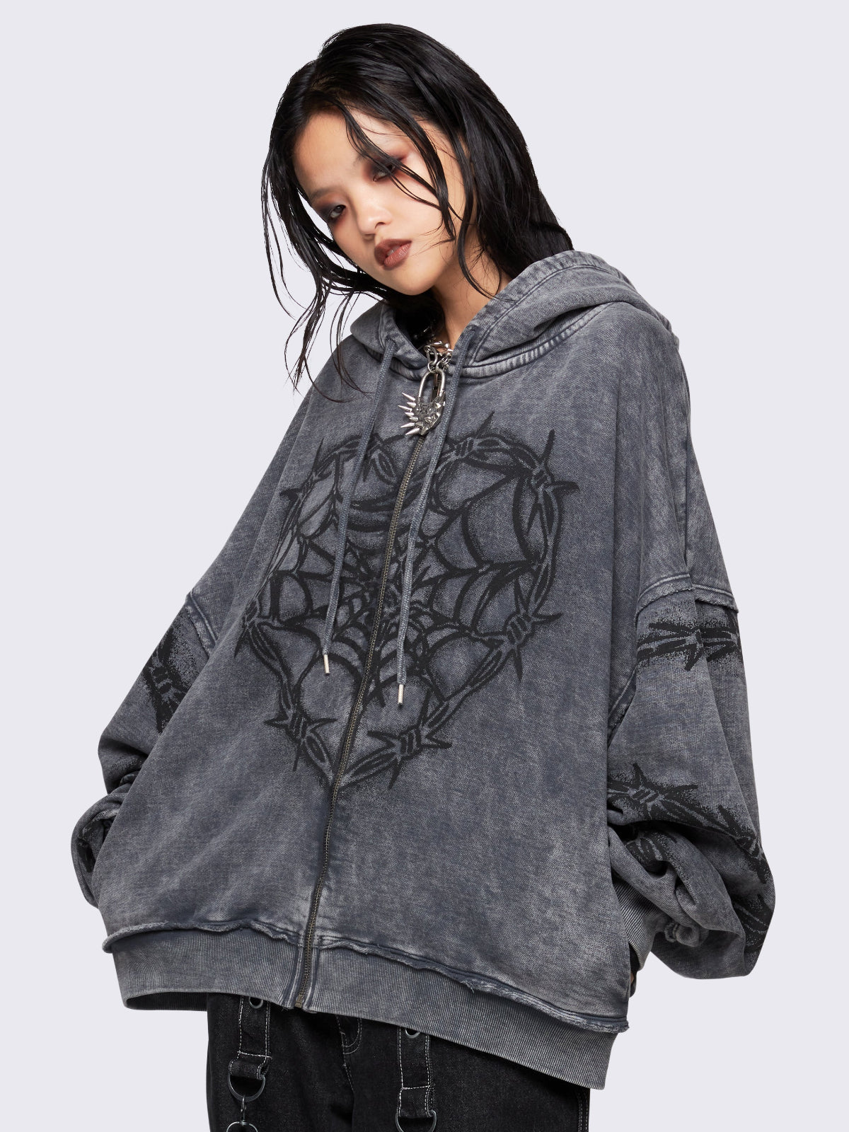 Grey distressed wash zip-up hoodie with a black barbed wire and spiderweb graphic, oversized fit, and dropped shoulders for a bold grunge aesthetic.