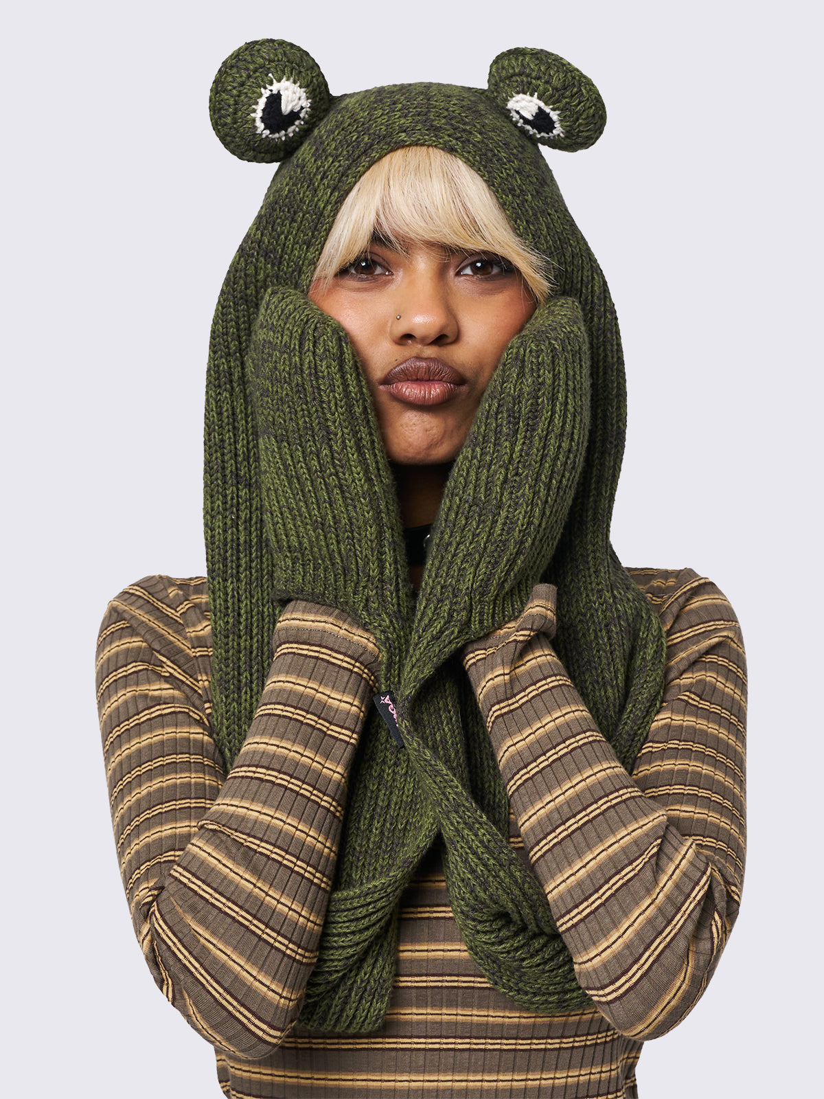 Knitted hooded scarf in green featuring a beanie-style hood with frog eyes and pockets at the scarf end.