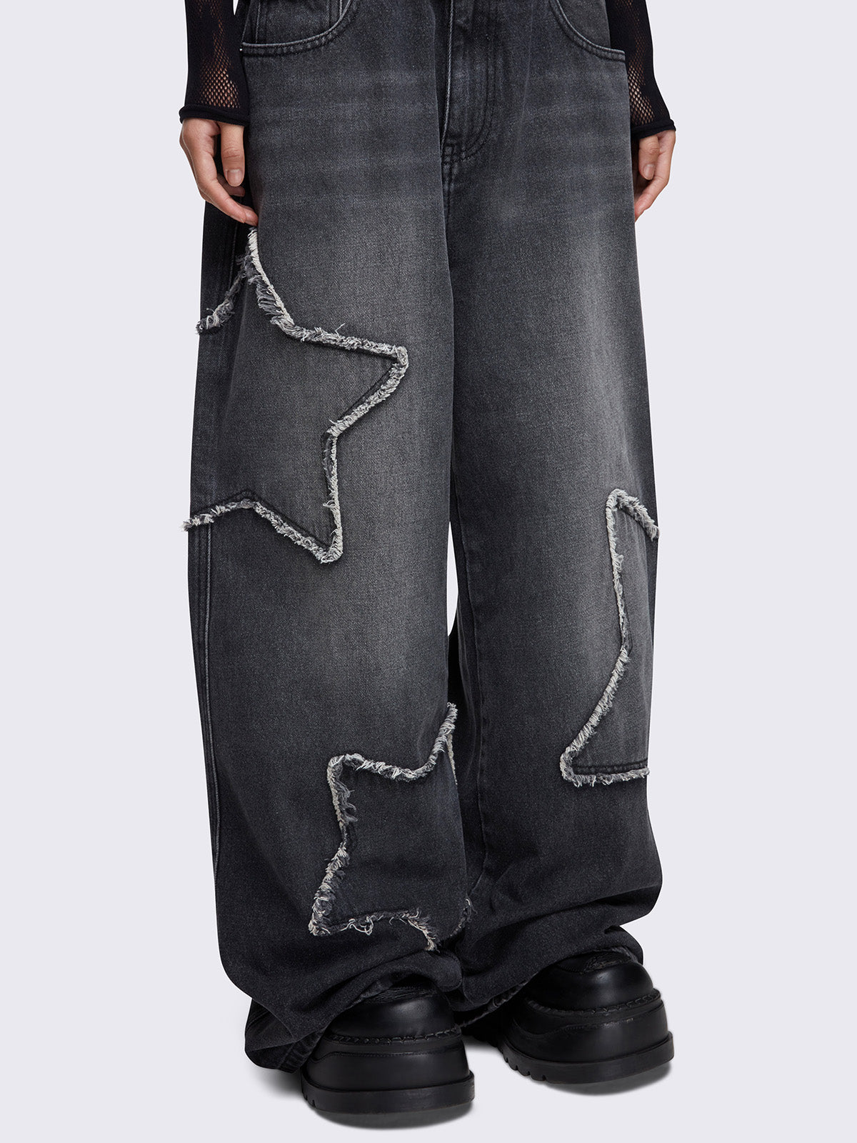 Baggy jeans in washed black with frayed star patches and wide leg fit. 