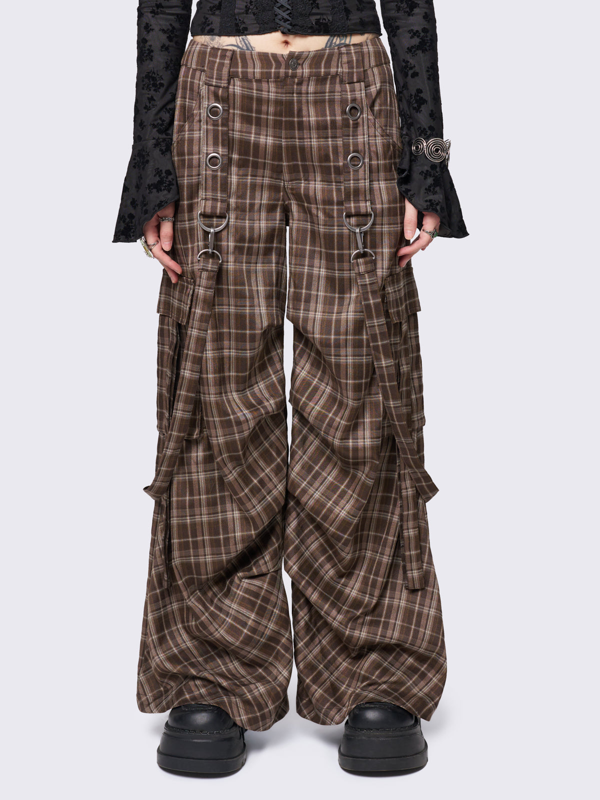 Brown plaid multi-pocket cargo pants with wide legs, featuring straps, eyelets, and D-ring details for a stylish utility-inspired look.