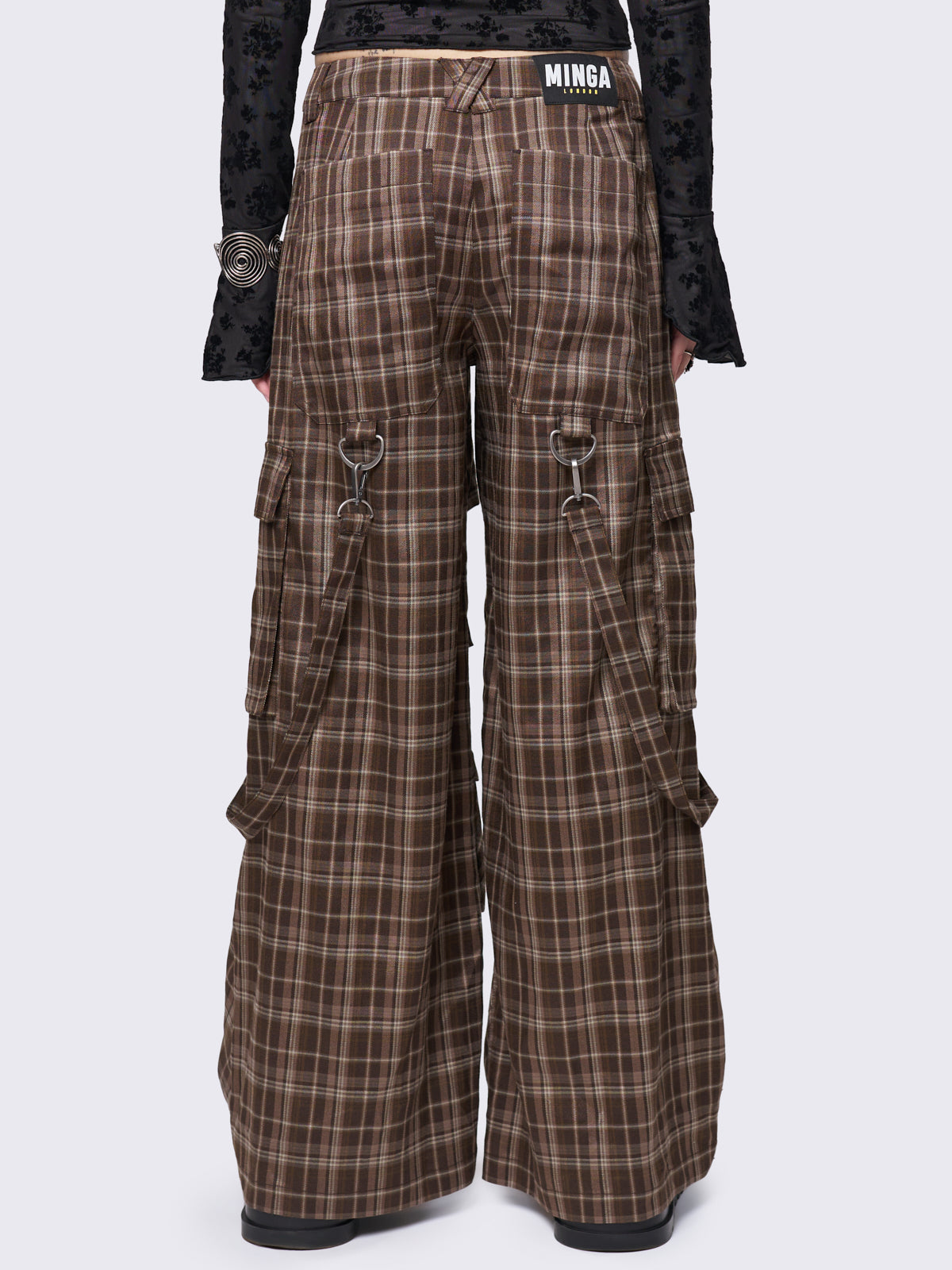 Brown plaid multi-pocket cargo pants with wide legs, featuring straps, eyelets, and D-ring details for a stylish utility-inspired look.